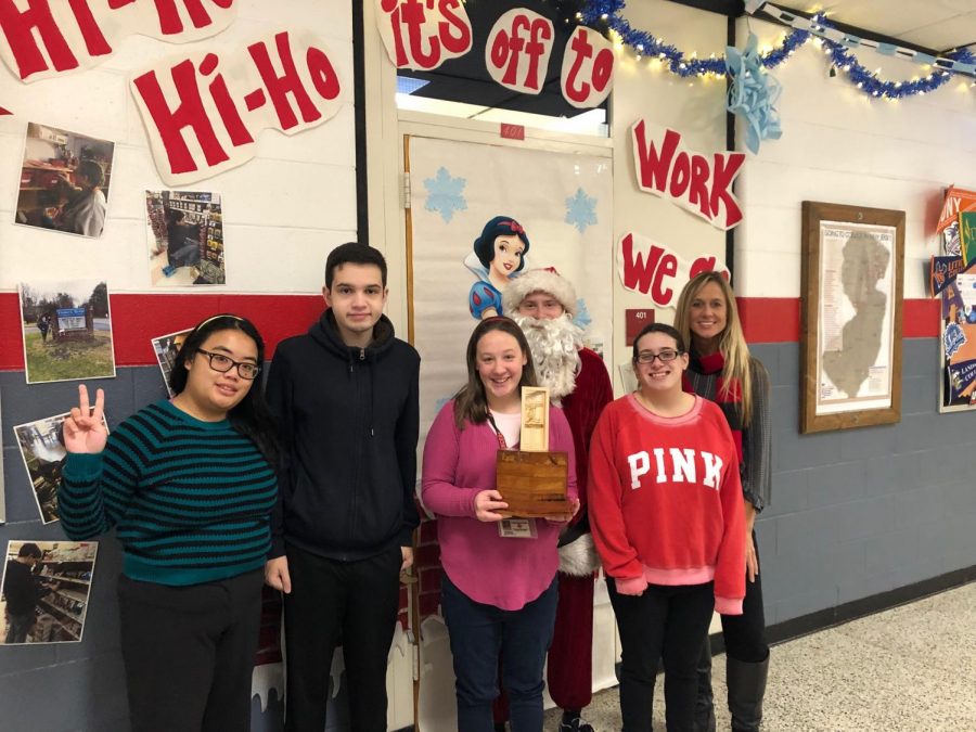 Ms. McCormack and STEP program students proudly posing with the Door Decorating trophy and in front of their Snow White and the Seven Dwarfs themed decorations.