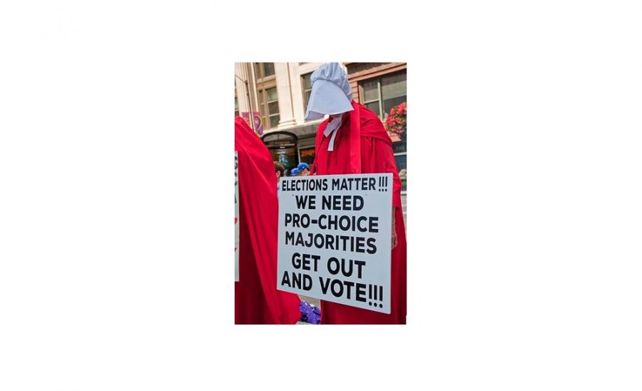 The reason for the controversy behind Kylies party - the handmaide as become of system for gender discrimination and oppression, like at this 2018 protest in Chicago to stop Brett Kavanaugh from being 
 sworn into the Supreme Court. 