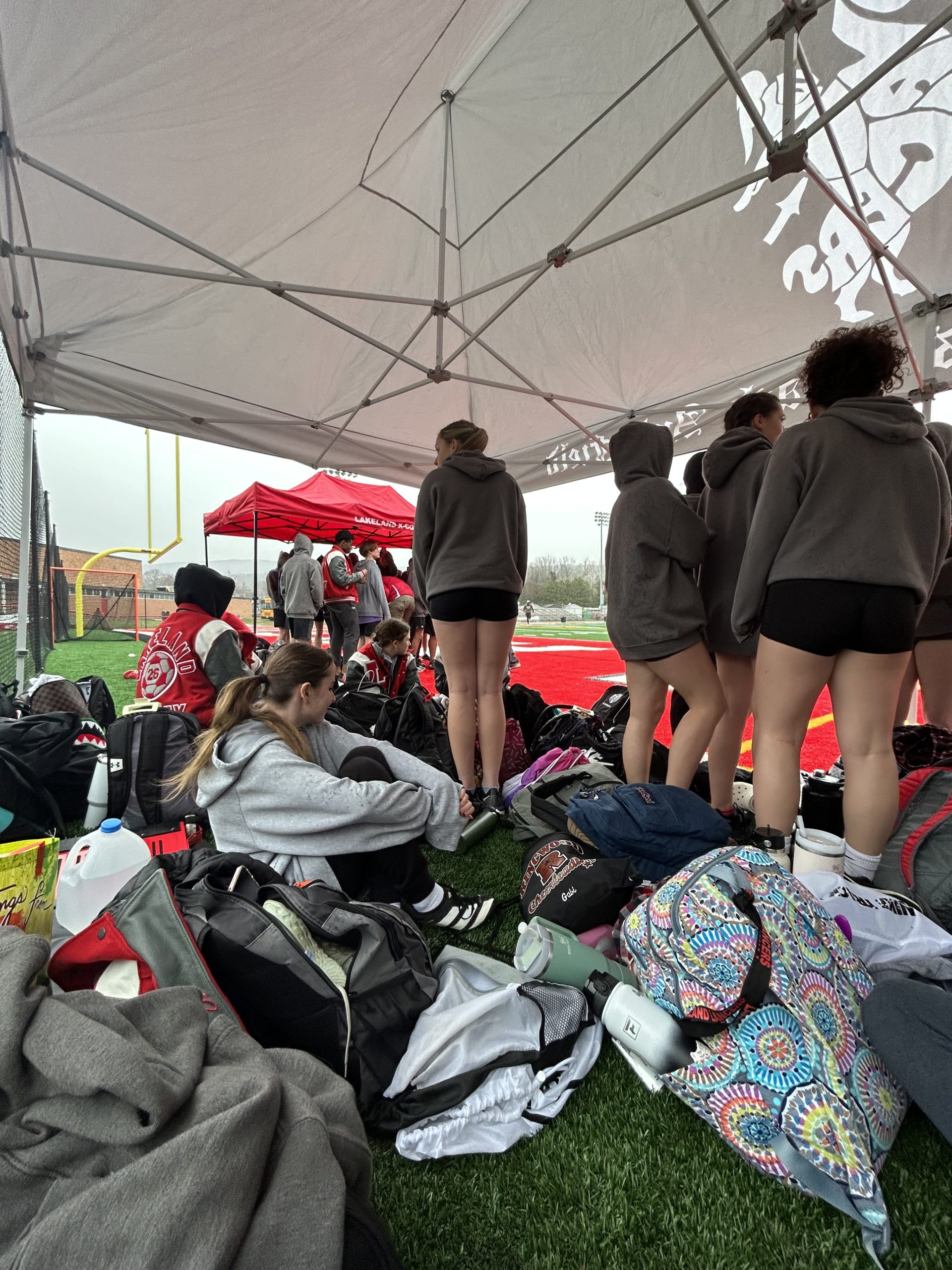 The Lakeland track team huddles underneath a tent during their first scrimmage of the season.